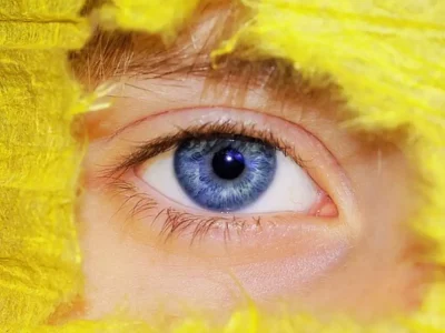 oeil humain bleu entouré d’un un tissu jaune oeil humain